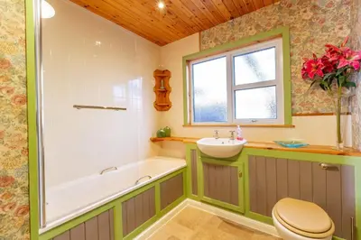 a bathroom with a tub and a sink and a toilet at Dunrod - Overlooking the bay in Kirkcudbright