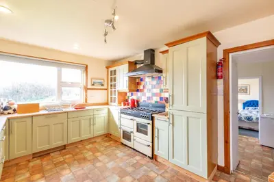 a kitchen with white cabinets and a stove top oven at Dunrod - Overlooking the bay in Kirkcudbright