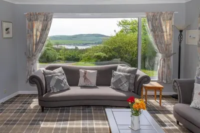 a living room with a couch and a large window at Dunrod - Overlooking the bay in Kirkcudbright