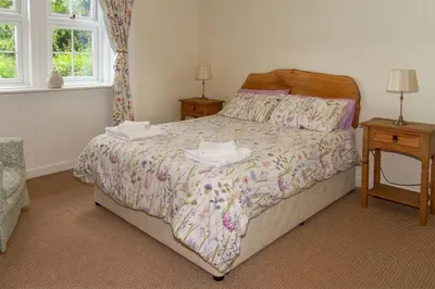 a bedroom with a bed with two tables and two windows at No2 Chapelton Cottage in Kirkcudbright