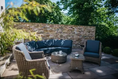 a patio with a couch and two chairs and a table at Mount Auldyn House - The Cottage in Ramsey