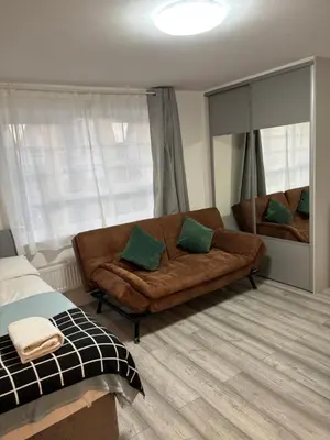 a living room with a brown couch and a mirror at private Studio with its own kitchen and bathroom in Moffat
