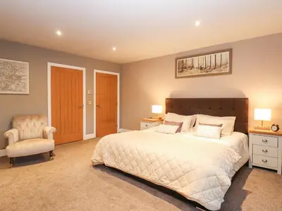 a bedroom with a large bed and a chair at The Steading in Dumfries