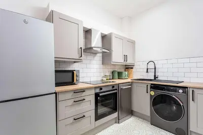 a kitchen with white cabinets and a washer and dryer at The Annick Suite No1 - Donnini Apartments in Irvine