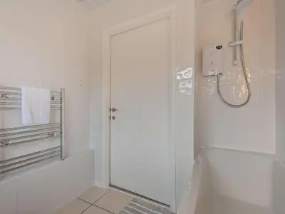 a white bathroom with a shower and a glass door at 3 Bed in Keswick 95858 in Keswick