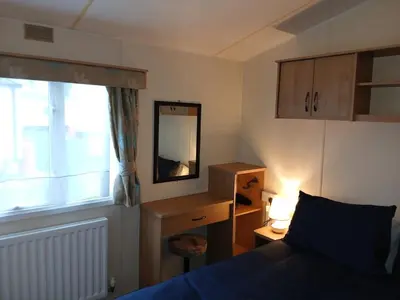 a bedroom with a bed and a mirror and a window at Harriet's Haven - Endless Pool, Tennis, Sky TV in Port Carlisle