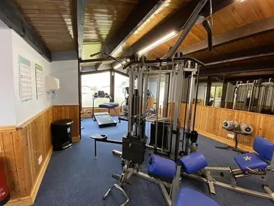 a gym with blue chairs and equipment in a room at Harriet's Haven - Endless Pool, Tennis, Sky TV in Port Carlisle