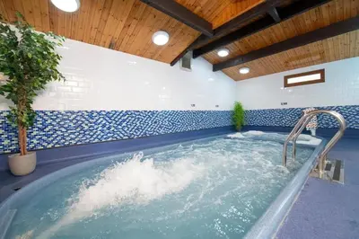a jacuzzi tub in a room with blue and white tiles at Harriet's Haven - Endless Pool, Tennis, Sky TV in Port Carlisle