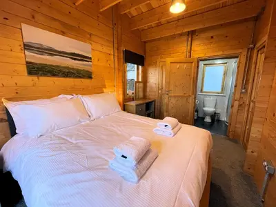 a bedroom with a bed in a wooden cabin at Beautiful Countryside Lodge with Outstanding Views - Pass the Keys in Dumfries