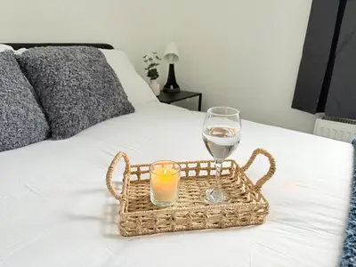 a basket with a candle and a glass of wine on a bed at Workington Home - Working - Visiting the Lakes in Workington