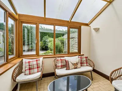 a conservatory with chairs and a table and windows at 3 Bed in Wigton oc-95374 in Uldale