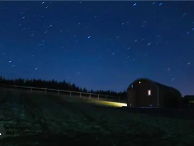 a barn sitting in a field at night at Barnharrow Holiday Pods in Newton Stewart