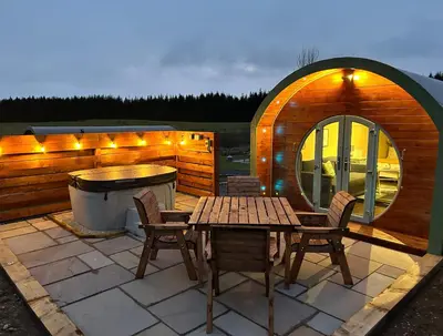 a patio with a table and chairs and a tub at Barnharrow Holiday Pods in Newton Stewart