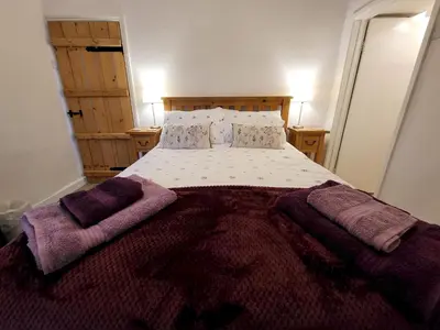 a bedroom with a large bed with purple blankets at Holly Cottage Grasmere in Grasmere