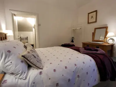 a bedroom with a white bed with flowers on it at Holly Cottage Grasmere in Grasmere
