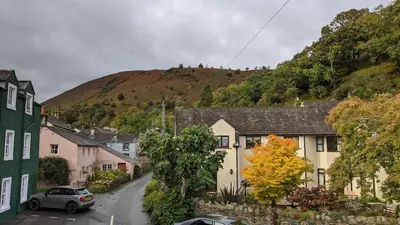 a small village with a hill in the background at Oakside Cottage Braithwaite in Braithwaite