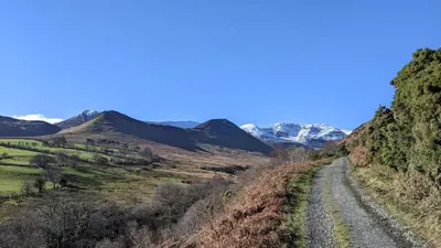 a dirt road with snow covered mountains in the background at Oakside Cottage Braithwaite in Braithwaite