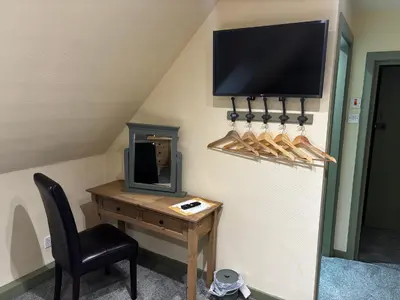 a room with a desk and a tv on a wall at The Bee Hive Hotel in Coylton