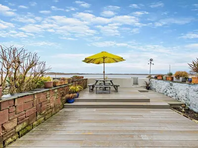 a table with a yellow umbrella on a patio at 2 Bed in Ravenglass oc-95884 in Ravenglass