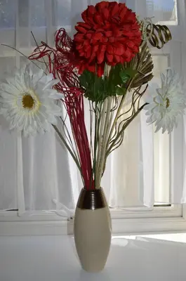 a white vase with red and white flowers in it at Sea Breeze Guest House in Douglas