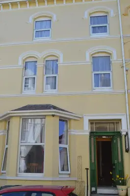 a yellow house with a red car parked in front of it at Sea Breeze Guest House in Douglas
