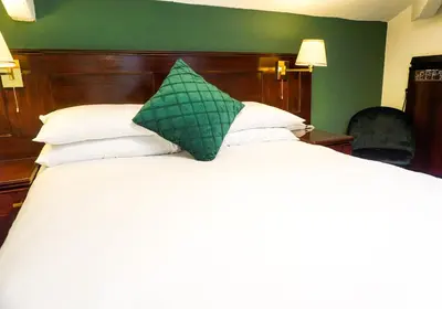 a bed with a green pillow on top of it at Manor House Hotel, Cockermouth in Cockermouth