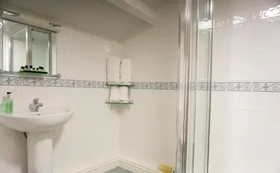 a white bathroom with a sink and a shower at Manor House Hotel, Cockermouth in Cockermouth