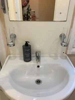 a woman taking a picture of a bathroom sink at Skiddaw Lodges- The Lake District in Plumbland