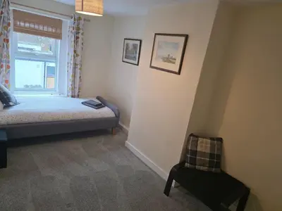 a bedroom with a bed and a window and a chair at Cute Cottage in Historic Port Carlisle 12miles from M6 in Port Carlisle