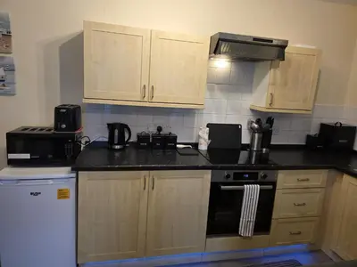 a kitchen with wooden cabinets and a black counter top at Cute Cottage in Historic Port Carlisle 12miles from M6 in Port Carlisle
