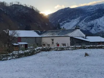 a house in a snowy field with the sun in the background at Field House in Keswick