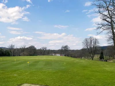 a golf course with a green field and trees at Fleet Townhouse in Gatehouse of Fleet