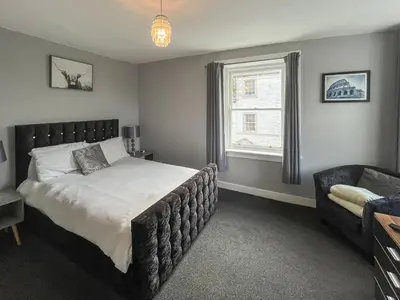 a bedroom with a bed and a chair and a window at Fleet Townhouse in Gatehouse of Fleet