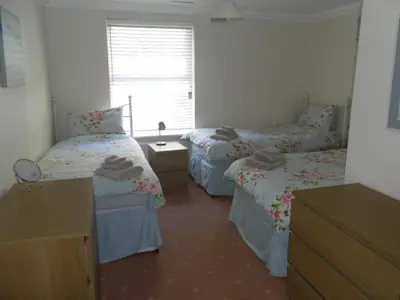 a room with three beds and a window at isle of man holiday apartment in Douglas