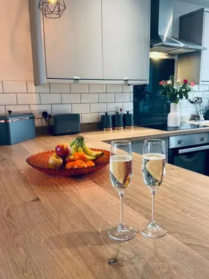 two glasses of wine and a bowl of fruit on a kitchen counter at Keekle Cottage - 2 Bedrooms - Sleeps 4 in Cleator Moor