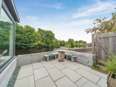 a patio with a table and a view of a river at Creebank Cottage with river view in Newton Stewart