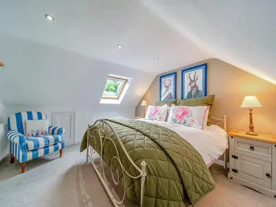 a bedroom with a bed and a blue chair at Creebank Cottage with river view in Newton Stewart