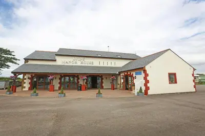 a large white building with a sign on it at Lyons Manor House Caravan Park in Mawbray