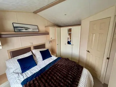 a bedroom with a bed with blue pillows at 28 The Beeches in Wigton