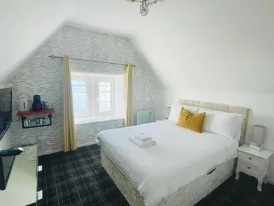 a bedroom with a large white bed and a window at Burlington Guest House in Whiting Bay