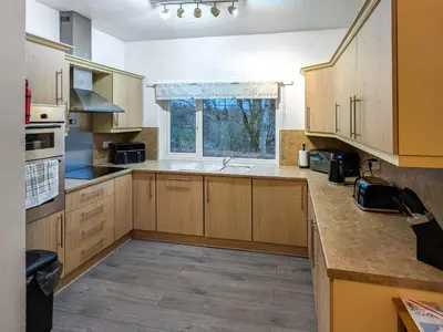 a large kitchen with wooden cabinets and a window at Prior Bank in Canonbie