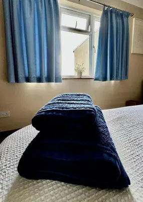 a blue blanket laying on a bed with a window at Airyolland in Newton Stewart