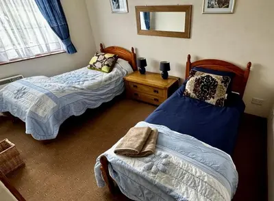 a bedroom with two beds and a dresser and a mirror at Airyolland in Newton Stewart