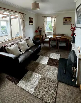 a living room with a black leather couch and a table at Airyolland in Newton Stewart