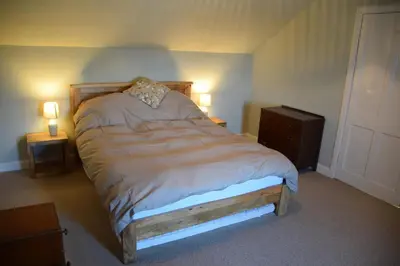 a bed in a bedroom with two night stands and two lamps at Albany Cottage in Rockcliffe