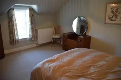 a bedroom with a bed and a mirror and a dresser at Albany Cottage in Rockcliffe