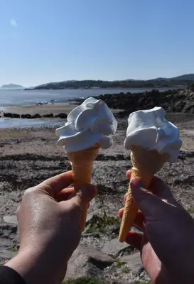 a person holding two ice cream cones on the beach at Albany Cottage in Rockcliffe