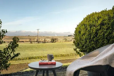 a table with a cup on top of it next to a field at The Retreat - Ridgestone in Penruddock