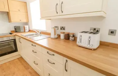 a kitchen with white cabinets and a wooden counter top at Ploughmans Cottage in Brampton