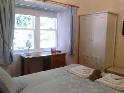 a teddy bear laying on a bed in a bedroom at Ardwell House East Lodge in Stranraer